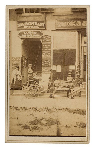 CDV of Photographic Studio, F.J. Moore, Westfield,: CDV of Photographic Studio, F.J. Moore, Westfield, Mass. A cdv photograph of the entrance to photographer F.J. Moore's studio, with two signs visible above the entrance and along the right side, plu