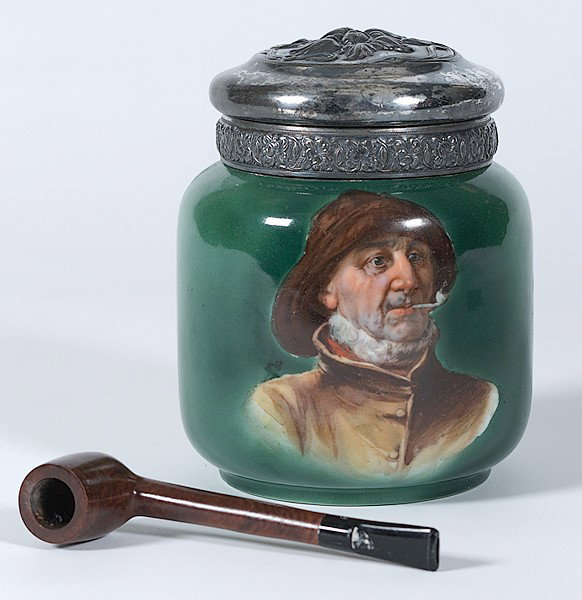 Porcelain Humidor : Porcelain Humidor 20th century, a porcelain humidor depicting a man smoking a pipe,on a green ground, with metal lid; plus wooden pipe; all unmarked; ht. 7 in., pipe lg. 6 in.