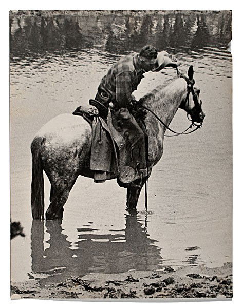 Charles J. Belden Photograph of a Cowboy & Horse a: Charles J. Belden Photograph of a Cowboy & Horse at a Watering Hole Silver gelatin photograph, unmarked, but by Charles Belden, capturing a cowboy on his horse at a watering hole, sipping water from