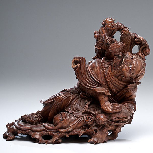 Chinese Boxwood Carving : Chinese Boxwood Carving Chinese, a boxwood carving of a lounging, bearded figure, dressed in flowing robes and sandals, resting on a cinnabar box, with an attendant pouring liquid from a teapot into