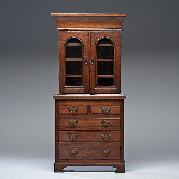 Miniature Stepback Cupboard : Miniature Stepback Cupboard American, mid-19th century, a miniature stepback cupboard in walnut having a deeply moulded cornice over two doors enclosing shelves in the upper case, the lower case wit