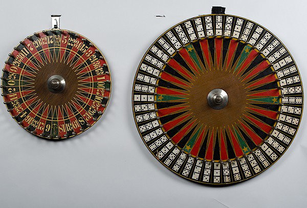 Antique Gaming Wheels : Antique Gaming Wheels American. Two gaming wheels including a roulette-style wheel and one with combination's of three dice (three-of-a-kind starred); largest dia. 23.5 in.