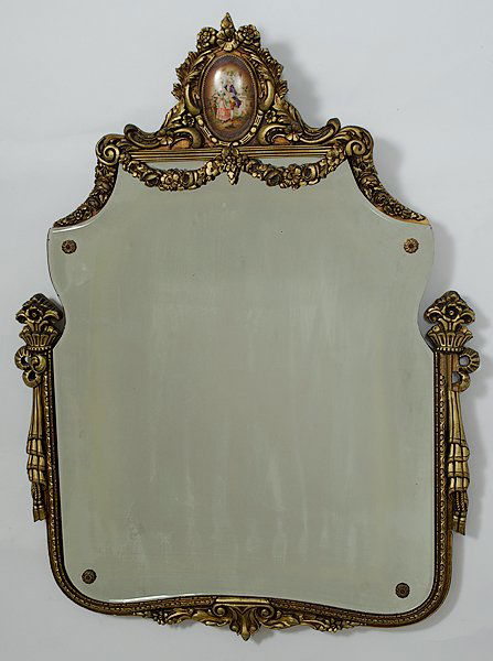 Carved Framed Mirror : Europe. A Continental carved floral frame mirror with center oval porcelain at crest of courting scene; frame is carved floral gold gilted design; ht. 32, wd 23 in.