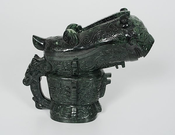 Ritual Wine Vessel : China. A Shang dynasty-style ritual wine vessel in spinach jade in the shape of a mythological beast with an animal head and covered in archaistic designs; unmarked; ht. 9.25 in. Provenance: Ex Coll