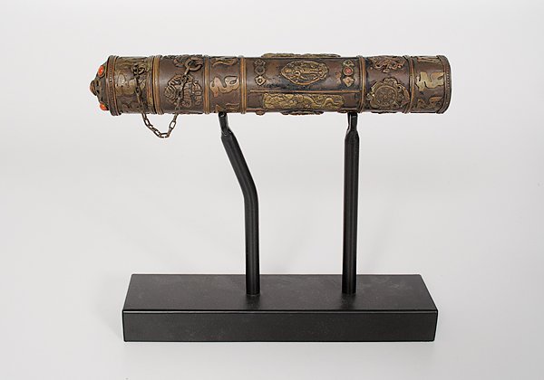 Chinese Brass Incense Holder : China. A brass lidded incense holder with inlaid red beads, having Buddhist decoration and calligraphic script in bands along the exterior, with a visvavajra emblem on the end, on a 20th century metal
