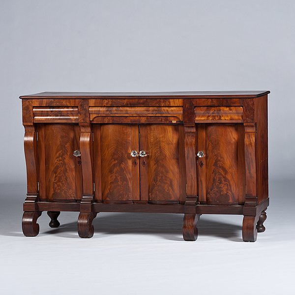 Late Classical Sideboard: Late Classical Sideboard American, ca 1825-1835. A Late Classical pillar and scroll sideboard in mahogany with poplar and pine secondary, having three drawers over four doors with pressed glass knobs,
