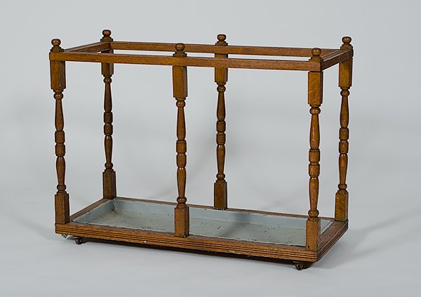 Umbrella Stand : Umbrella Stand 20th century, an umbrella stand in oak with turned legs and a metal tray, all on casters; ht. 29.5, wd. 39, dp. 16.5 in.