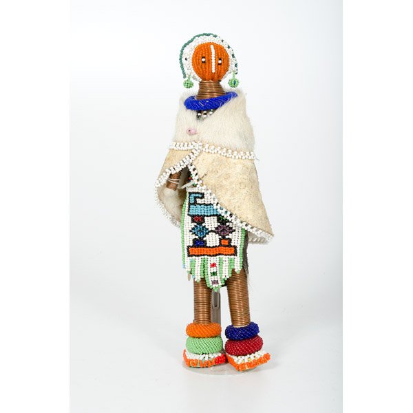 African Ndebele Initiation Doll : African Ndebele Initiation Doll Africa, 20th century, a African woman with beaded face, hair, headdress, earrings and beaded donuts around shoulders and ankles, a goat skin cape over a multi colorfu