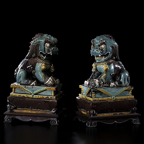Sancai Foo Dogs : Sancai Foo Dogs Chinese, 19th century. A sancai pair of ceramic foo dogs in blue, purple, and mustard yellow glaze, each on a wooden stand, unmarked; ht. 14 in. (with stand). Provenance: Ex L