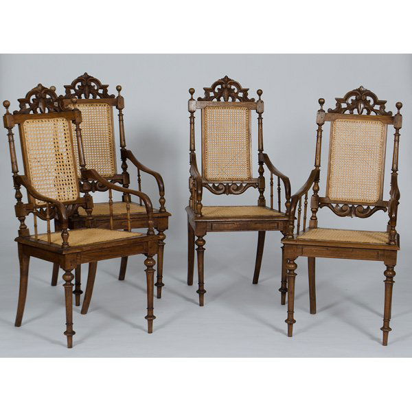 Caned Carved Oak Armchairs : American, 20th century. A set of four oak armchairs with caned seats and backs, having pierced foliate carved crests, ball finials and turned legs; ht. 44.75, seat ht. 17.75 in.
