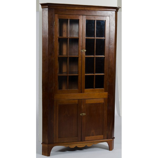 Walnut Corner Cupboard : American, 19th century. A corner cupboard in walnut having a molded cornice over two eight-pane doors over two paneled doors, all rising on a shaped skirt and bracket feet; ht. 84.5, wd. 45 in.