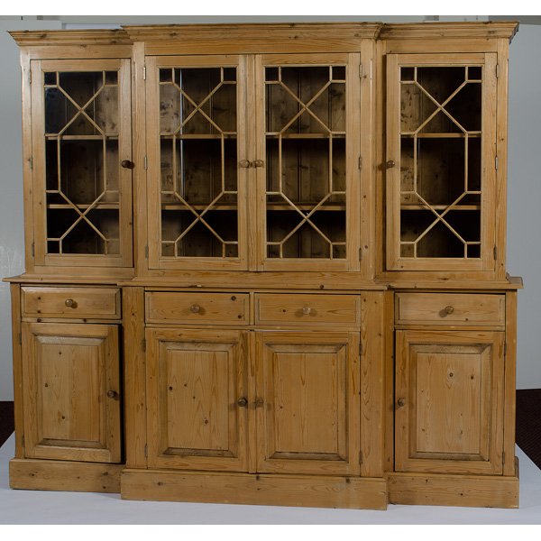American Pine Breakfront : American, 20th century. A provincial two part breakfront in pine having a molded cornice above a case fitted with four glazed doors, the lower section fitted with four drawers over four paneled doo