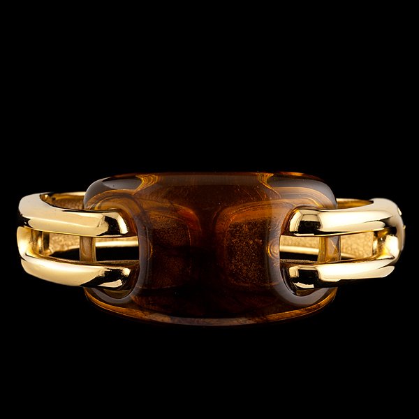 Givenchy Amberlite Bangle : A gold tone bracelet with side hinge and center amberlite stone, marked Givenchy, Paris, New York, 1976; wd. 2.3 in. Provenance: Property from the Collections of Carole Tanenbaum, Toronto, Canada.