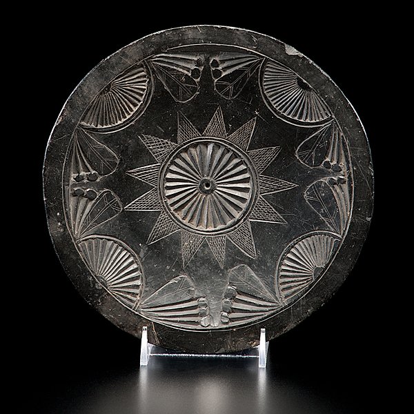 Haida Argillite Plate : both sides decorated with fan and leaf motif, starburst in center and reverse with crosshatching; center of plate pierced, diameter 7 in. mid-19th century