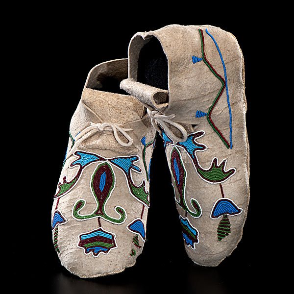 Crow Beaded Hide Moccasins : sinew-sewn elk(?) and beaded using colors of rose, pea green, light and medium blue, and white; outlined geometrics and florals decorated vamps, length 10 in. early 20th century