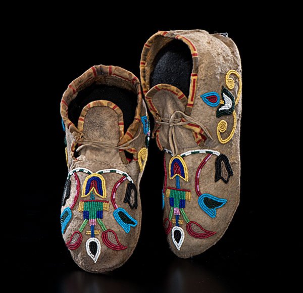 Crow Beaded Hide Moccasins : thread and sinew-sewn and beaded using greasy yellow, light blue, cobalt, red white-heart. white, and pink; with outlined florals and geometrics on vamps and cuffs; cuffs edged in yellow and red cotto
