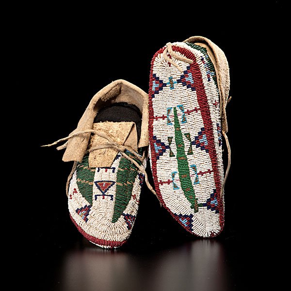 Sioux Fully Beaded Hide Moccasins : sinew-sewn and beaded using colors of light blue, dark blue, red white-heart; white, and clear; buffalo tracks and dragonfly designs decorated moccasins; sole with geometrics, length 10 in. late 19th 