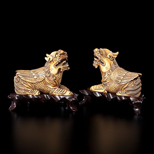 Chinese Ivory Mythological Beasts : Chinese, early 20th century. A pair of carved and inked ivory mythological beasts, each unmarked, on fitted wooden stands and housed in cloth-covered box; ivory ht. 2.75, lg. 3.5 in.