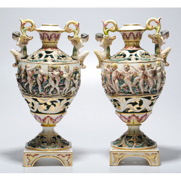 Capodimonte Urns : Continental, 19th century. Pair of porcelain urns with a band of dancing cherubs and handles of winged goddesses, marked underneath base 645 Capodimonte Italy; ht. 15.5 in.