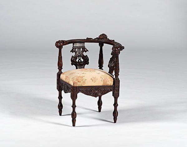 Continental Carved Corner Chair : Continental, 19th century. A carved mahogany corner chair, with crest of female head, lion terminals, carved and pierced splats of mythological beasts, above an upholstered seat, carved chair rail an