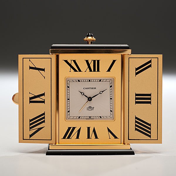 Cartier Triptych Clock : French & Swiss, ca 1992. A triptych clock with an alarm function controlled by a winding crown and a sunburst pattern on the exterior of the clock casing, lot includes the original Cartier case, box