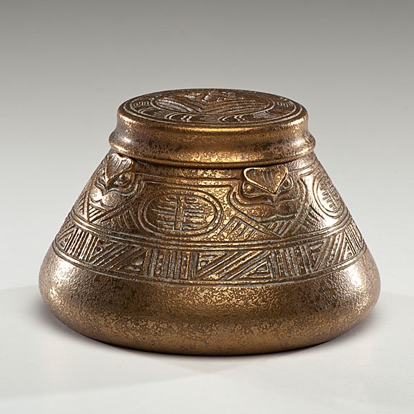 Tiffany Studios American Indian Pattern Inkwell : American, early 20th century. A Tiffany Studios bronze inkwell in the American Indian pattern, with hinged lid and glass insert, marked Tiffany Studios / New York / 1183 on underside; ht. 3.75, dia. 5