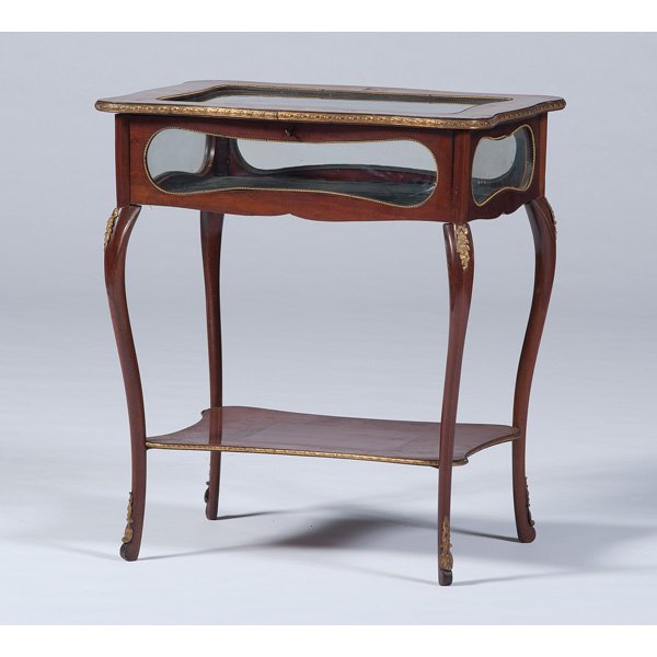 Louis XV-Style Vitrine Table : Continental. A Louis XV-style vitrine table in mahogany and mixed woods with ormolu mounts, having a shaped rectangular hinged top with ormolu banding and floral inlays surrounding a glazed panel, the