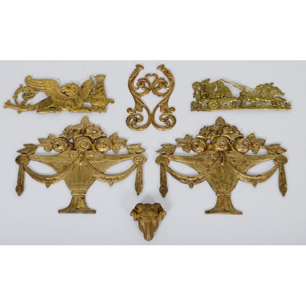 Collection of Ormolu Mounts : A group of six ormolu mounts, including one fine repousse scene of a classical female in a horse-drawn chariot, a lion flanked by a lightning bolt, a symmetrical arabesque form, a pair of flower urns