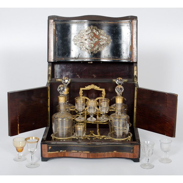 Tantalus Box with Assembled Glassware, Plus : Continental, 19th century. Ebonized tantalus box with mother of pearl, wood, and brass inlay, containing four gilt painted bottles with fitted stoppers and four cordial glasses that appear original