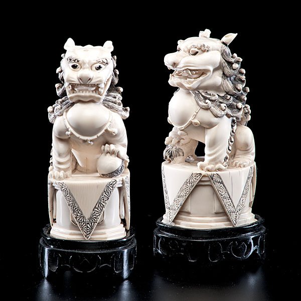 Chinese Carved and Inked Ivory Foo Dogs : Chinese. A pair of Foo dog guardians, each resting on altar stands in ivory; ht. of each 7.5 in. (w/stands)