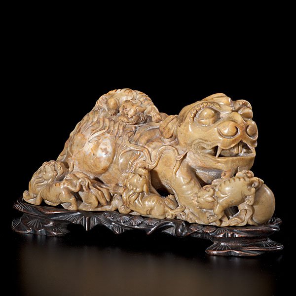 A Chinese Carved-Soapstone Buddhistic Lion Group : Chinese, late 19th/early 20th century. A greenish-yellow soapstone Buddhistic lion group carved with one large beast standing upon rockwork, three small cubs clamber around its feet while one cub pe