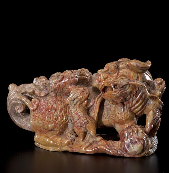 A Chinese Carved-Soapstone Buddhistic Lion Group with: Chinese, late 19th/early 20th century. A soapstone Buddhistic lion group carved with one large beast standing upon rockwork, its head turned directly to the right where three small cubs playfully en