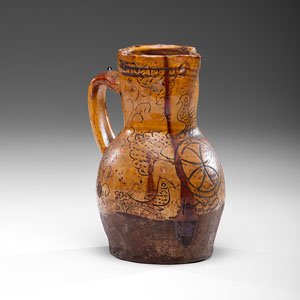 English North Devon Slipware Manganese Glazed Redware: English North Devon Slipware Manganese Glazed Redware Jug English (North Devon), early 19th century. A glazed redware jug with scrafitto floral and bird decorations; ht. 10.25 in.