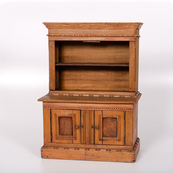 Miniature Open Pewter Cupboard : Miniature Open Pewter Cupboard American, 19th century. A miniature pewter cupboard in mixed woods, having a carved molded cornice and open top, the lower section with two paneled doors and a carved 