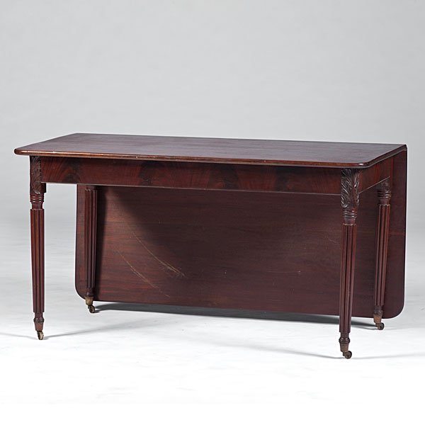 Classical Mahogany Banquet Table : Classical Mahogany Banquet Table American, 19th century. A mahogany dining table having one drop leaf, carved acanthus leaf front corners and rising on reeded legs, ending in thimble feet in brass c
