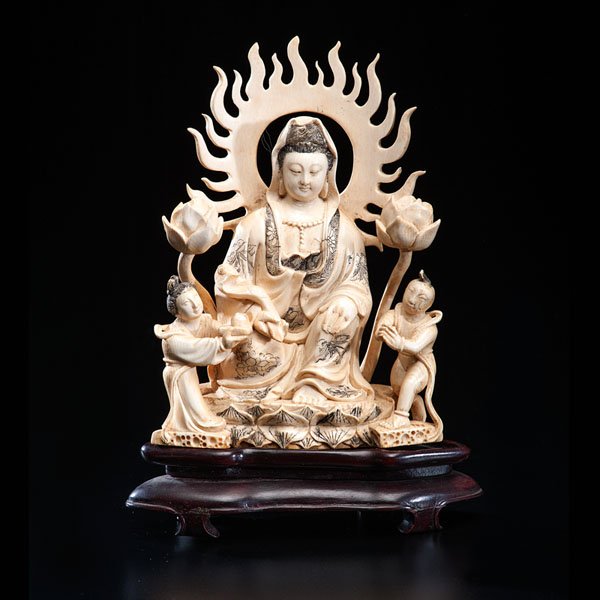 A Chinese Ivory Carving of a Deity : A Chinese Ivory Carving of a Deity Chinese, 19th century. An inked ivory carving of a Buddhist deity, with Tibetan influence. The deity, sitting in the center on a lotus throne, is flanked by two at