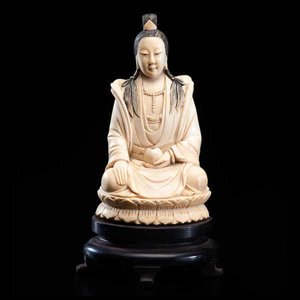 A Chinese Inked Ivory Carving of a Deity : A Chinese Inked Ivory Carving of a Deity Chinese, early 19th century. A carved and finely polished ivory carving of a deity seated on a lotus throne, holding a bowl. The figure rests on a wood stand