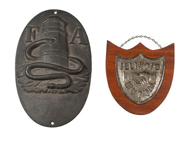 Firemarks : Firemarks American, 19th and 20th centuries. An oval-shaped cast iron firemark having the letters F A, and a second firemark in the form of a shield, made from wood and pressed tin, labeled on verso