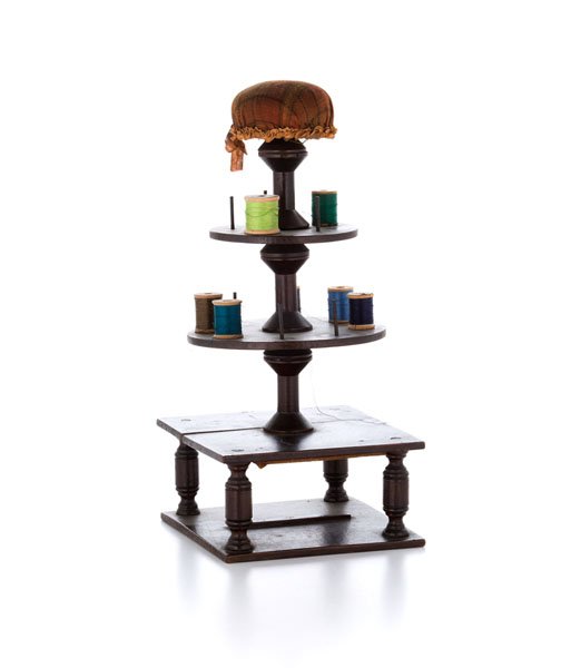 Walnut Sewing Caddy : Walnut Sewing Caddy American, 19th century. A sewing caddy in walnut in tower form with square base shelf and two rising circular spool shelves on turned baluster supports, topped with plaid fabric 