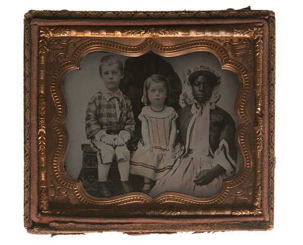 Striking Sixth Plate Ambrotype of a Female Slave: Striking Sixth Plate Ambrotype of a Female Slave, Two White Children, & their Mother Hand-tinted, sixth plate ambrotype of a female slave, possibly a nurse, posed with two white children, taken ca 1