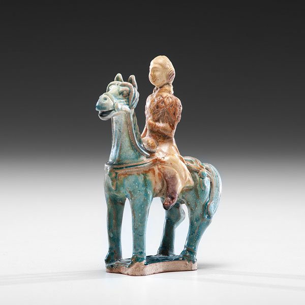 Small Tang Dynasty Earthenware Figure : Small Tang Dynasty Earthenware Figure Chinese, Tang dynasty. An earthenware figure on horseback covered in a blue and brown glaze. Ht. 5.25 in.; lg. 4 in.