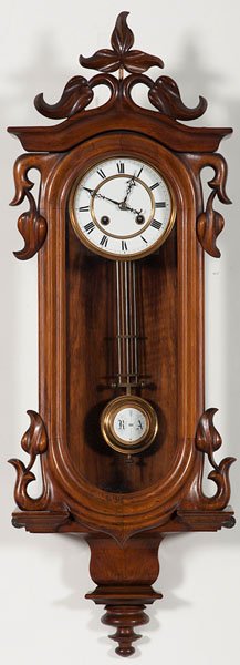 German Wall Timepiece : German Wall Timepiece German, late 19th century. A wall clock with a walnut case with carved stylized flowers, eight-day time and strike on gong, spring driven, R-A pendulum, with key; ht. 33, wd. 1