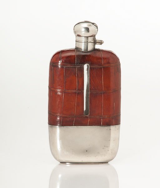 English Alligator and Silver Covered Flask : English Alligator and Silver Covered Flask English, 20th century. A glass flask encased in alligator leather, with the bottom having a removable silver cap marked Walker & Hall; ht. 7.25 in.