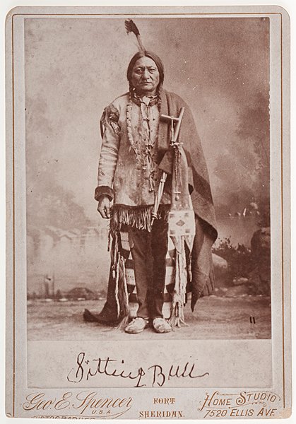 Sitting Bull Cabinet Card by George Spencer : Sitting Bull Cabinet Card by George Spencer Silver gelatin cabinet photograph of Sitting Bull, in traditional dress, standing with a pipe and beaded tobacco bag. Sitting Bull's signature in the prin