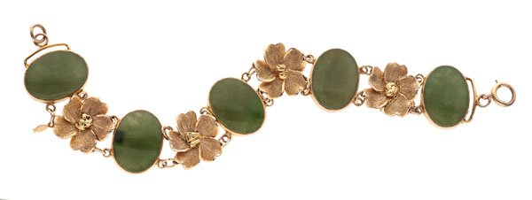 Jade Bracelet with Floral Accents in 10 Karat : A 10k yellow gold jade bracelet with floral accents. Featured are five 19mm x 14mm oval jades which are bezel set, separated by four gold flowers. Jump ring catch with safety chain. 15.8 dwt. Lengt