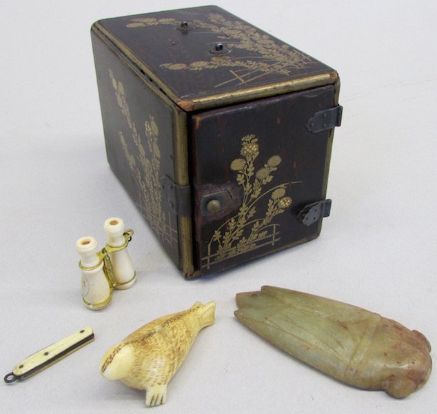 Japanese Lacquered Box and Two Carved Inro: The Lacquered box with overall black ground and gold floral decoration, the hinged door opens to three drawers. The intro in the form of a carved bone walrus and a carved hard stone Scarab Beetle. The