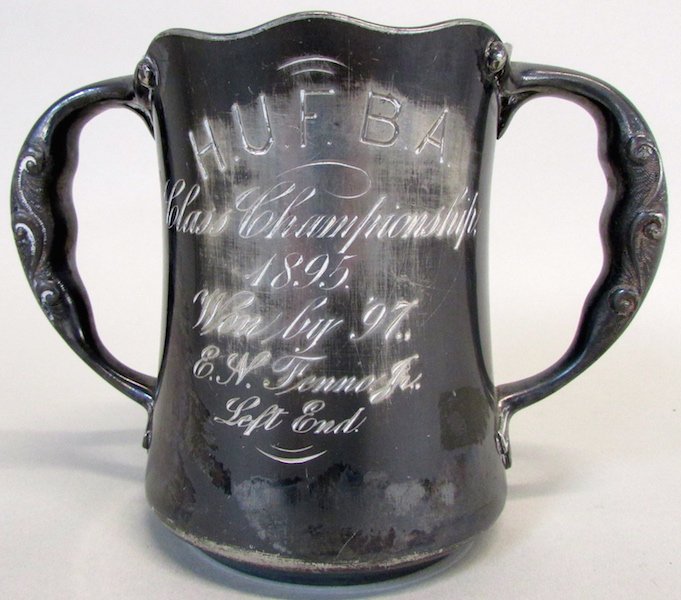 Harvard University Football 1895 Silver Cup: The double handled silver plated cup engraved "H.U.F.B.A. Class Championshipp, 1895, Won by '97, E.N. Fenn, Jr. , Left End." The cup by N.G. Wood and Sons, Boston. Height 5 1/4 inches.