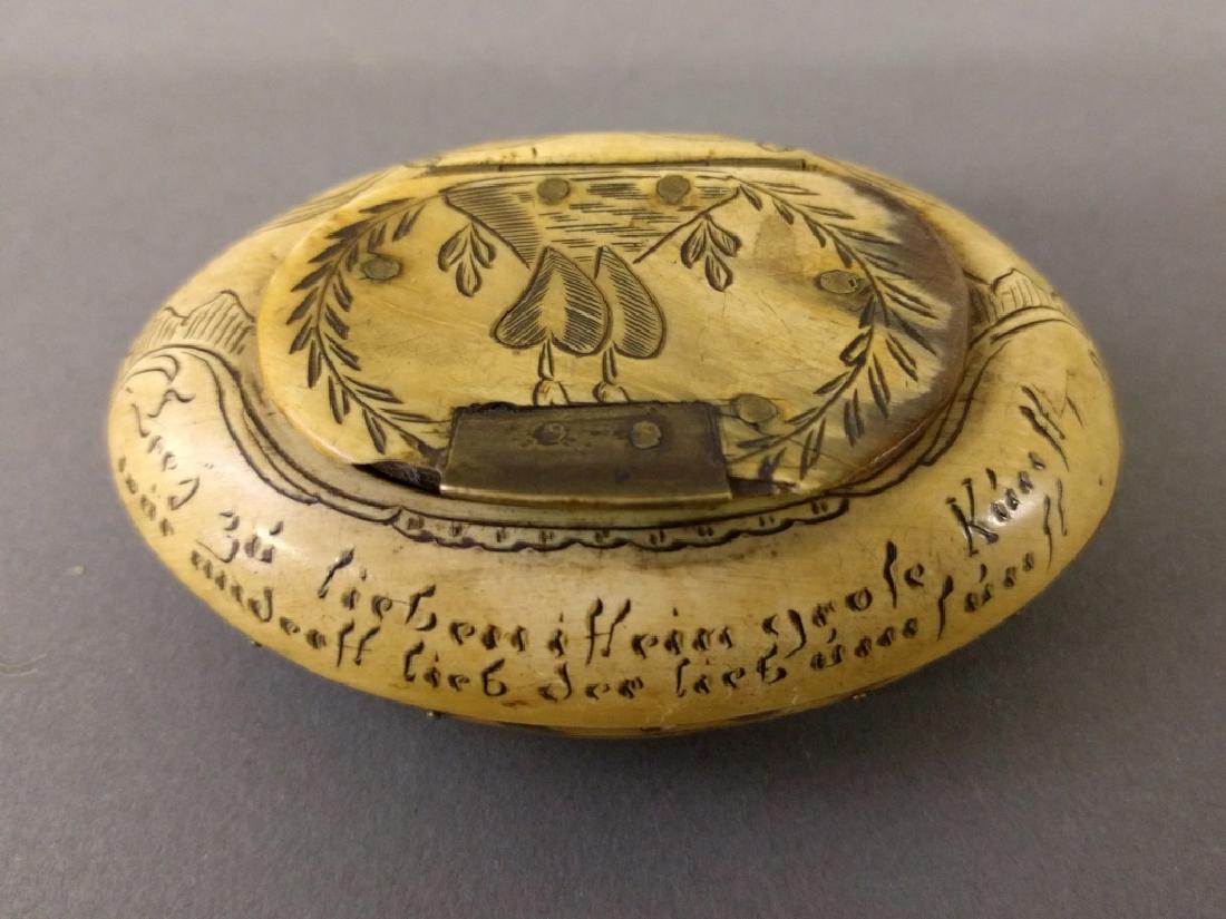 Carved snuff box: German carved oval bone snuff box, 19th century, with incised figures and verse. 1.25"h. x 3"l.