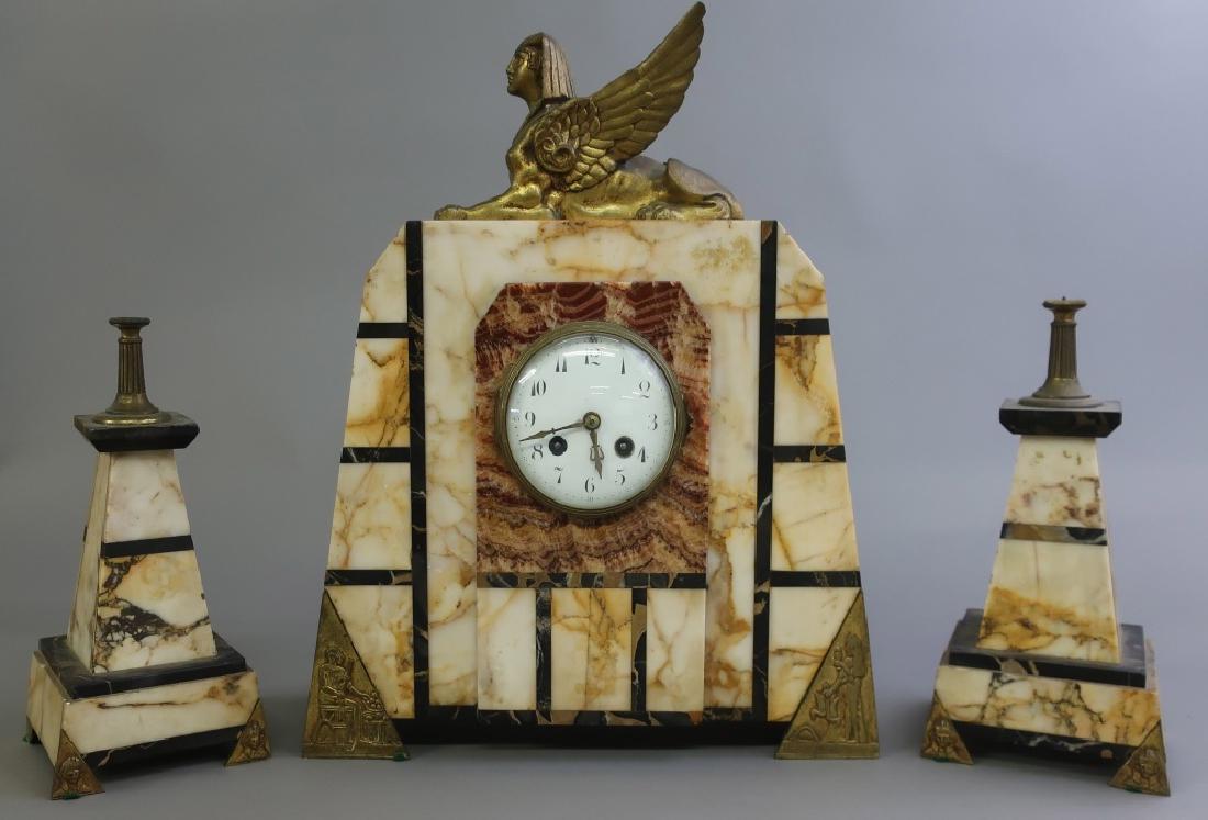 Egyptian Revival Marble and Bronze Clock Set: Egyptian Revival marble and bronze three-piece clock set, circa 1920's, clock 17"h x 13 3/4"w x 4 1/2"d, and two accompanying obelisk garnitures W.A.I. does not guarantee clocks to be complete or in w