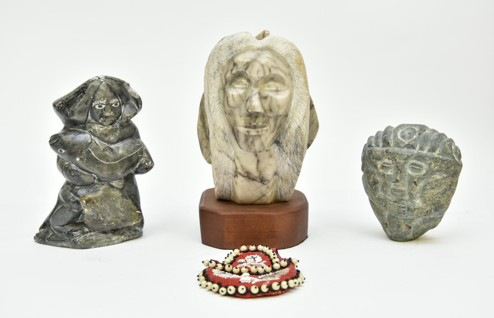 Three Stone Carvings etc.: There stone carvings including an Indian with feathers, signed N. Jushi, largest 10"h x 6"w; together with a beadwork pouch